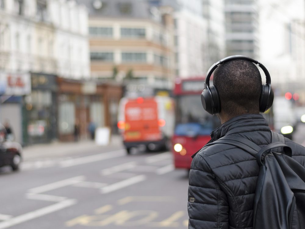 Person walking with headphones in city traffic