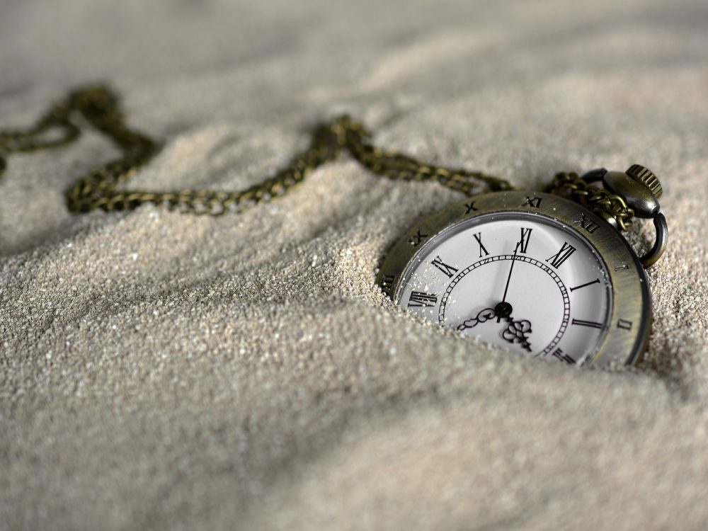 Pocket watch sinking in sand