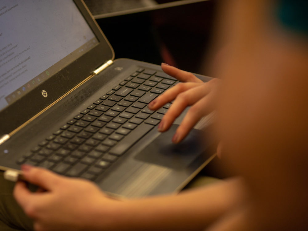 A student moves their finger across a trackpad on a laptop computer