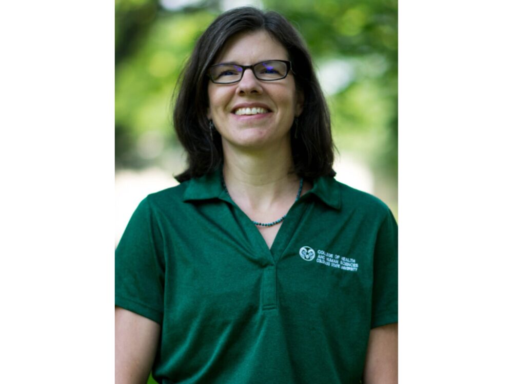 Portrait of Jen Garvey smiling while outdoors on a sunny, summer day.
