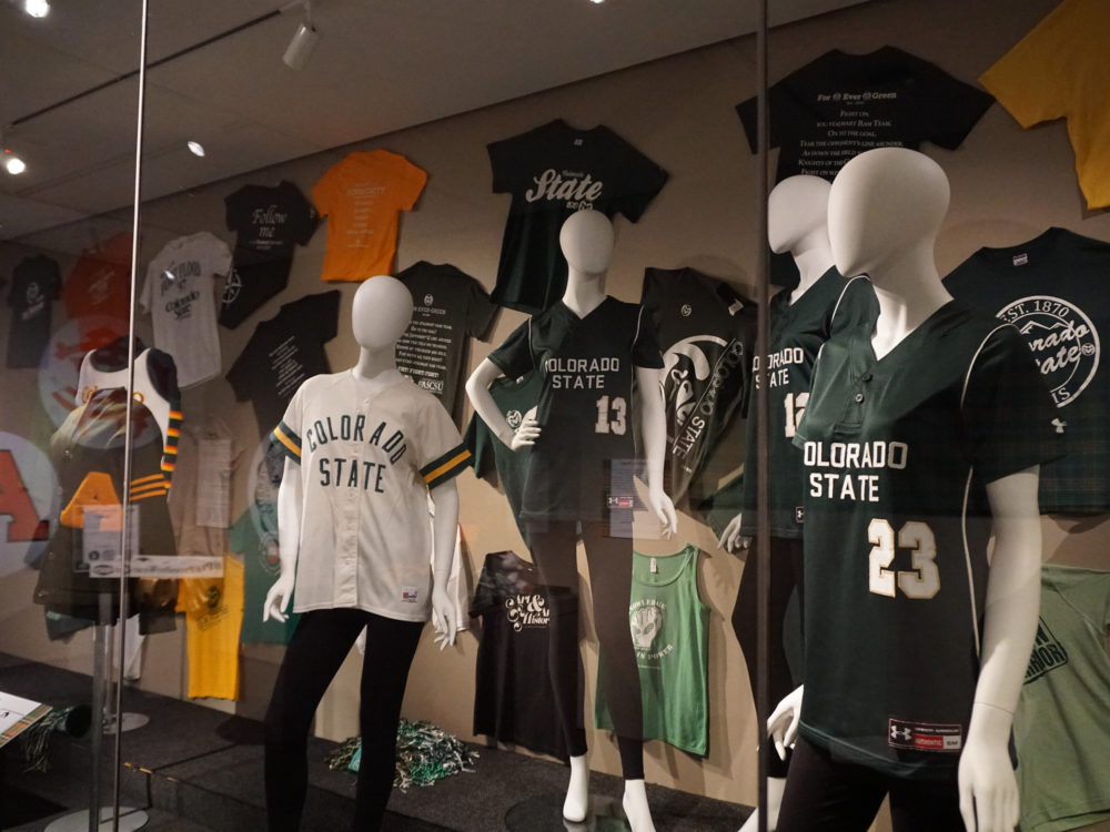 Proud to Wear CSU, 4 dress forms in CSU gear with a wall of historic CSU tshirts behind them on display in the Richard Blackwell Gallery