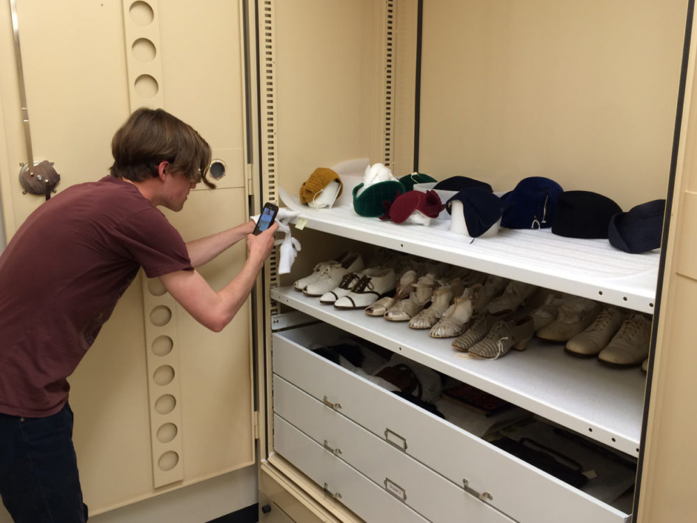 A student photographs shoes in a cabinet