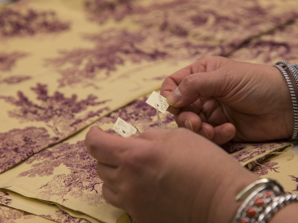 Closeup of hands holding lables and a textile in the background