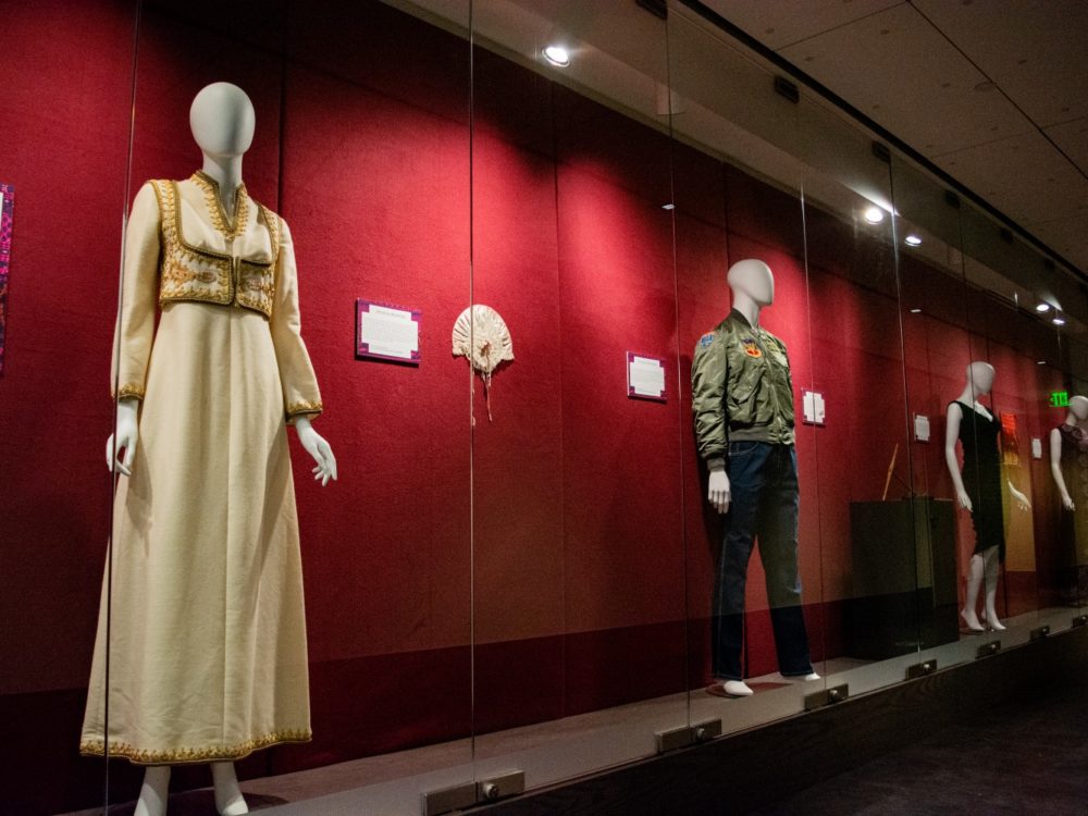 An exhibit with a gown and male clothing