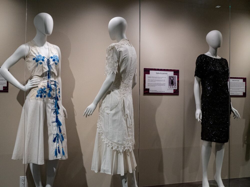 Three mannequins behind glass wearing dresses
