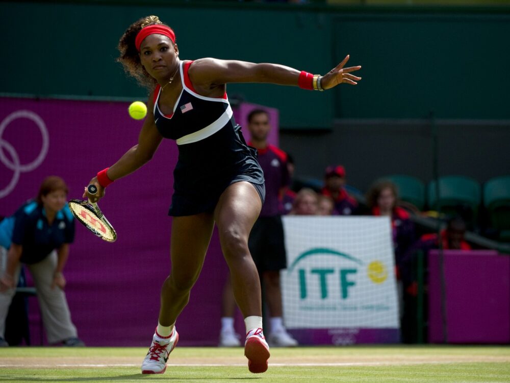 Serena Williams hitting a tennis ball in a blue dress