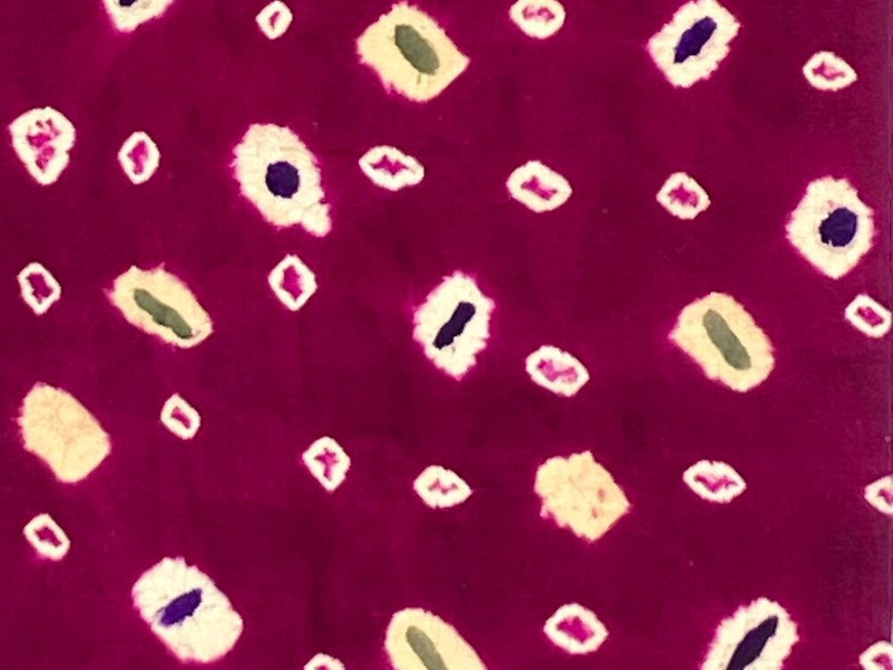 a close up of fabric created from resist dyes with a purple background and spots where resists were created.