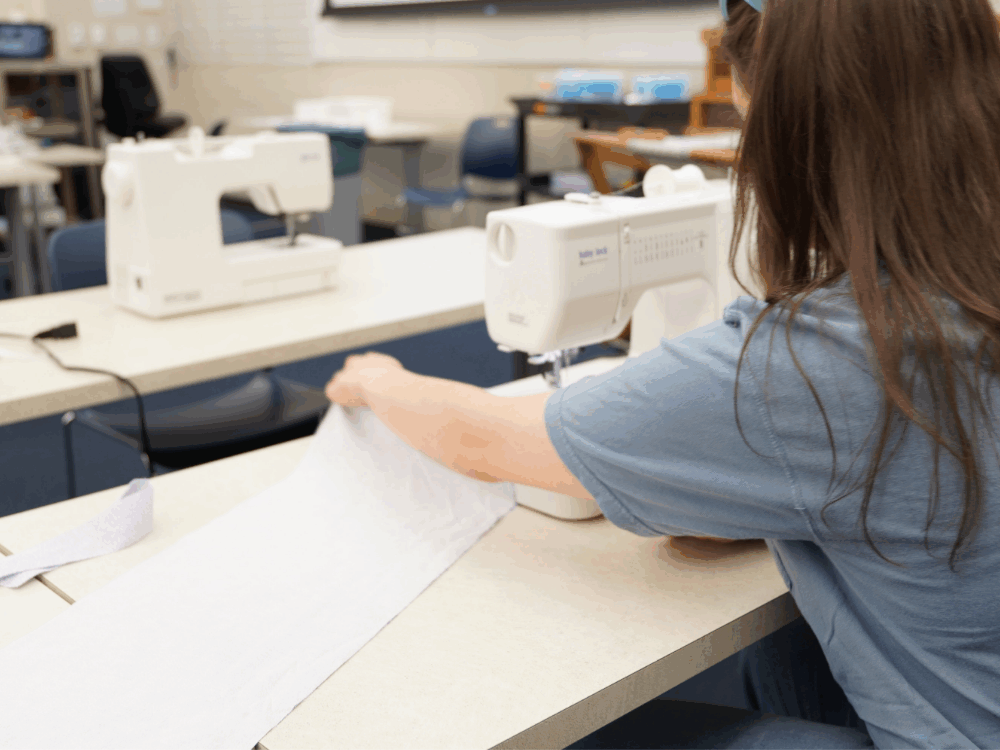 A person sits at a sewing machine.