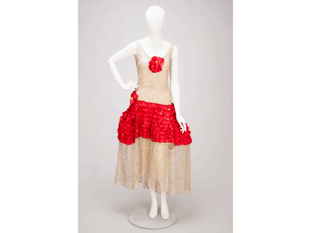 An image of a robe de style made of metallic gold lace with bright red ruffles at the waistline.