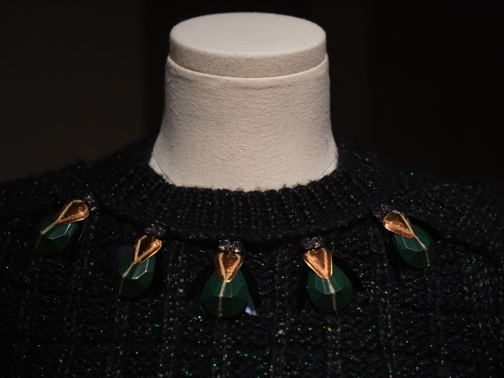 A detail image of the neckline of a Tori Burch sweater with beetles made of beads on the neackline.