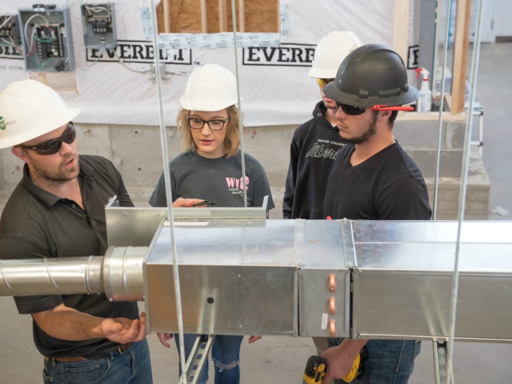 CM instructor showing 2 male students the components of an HVAC system