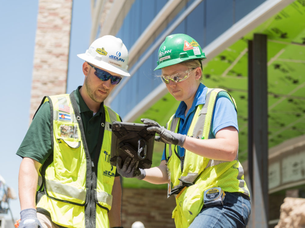 Male and female in construction hardhats on jobsite