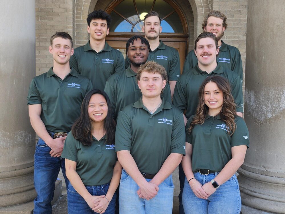 A photo of the design build team, including nine members, all wearing matching green polos