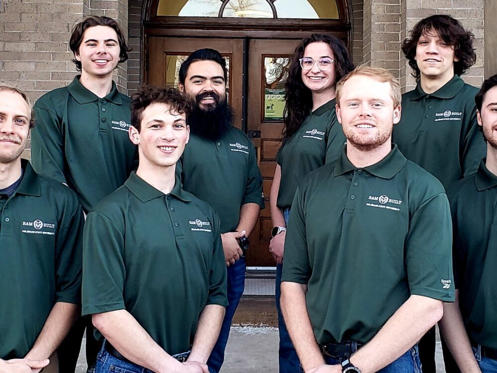A photo of the preconstruction team, including eight members, all wearing matching green polos