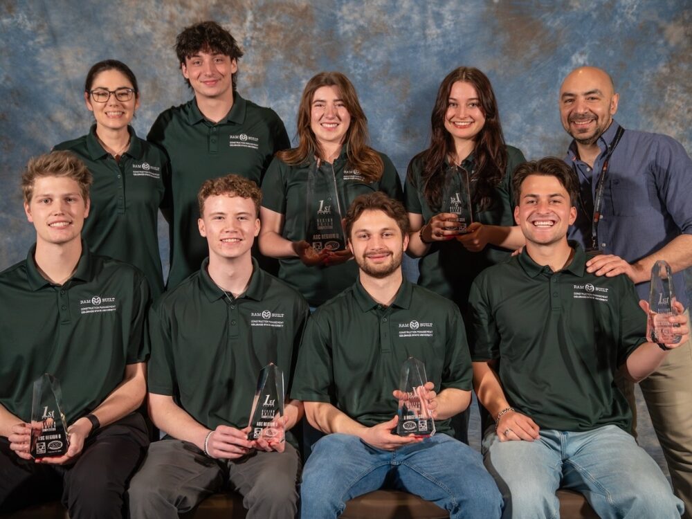 A group of nine CSU construction management students and faculty smile while holding 1st place trophies at a competition.