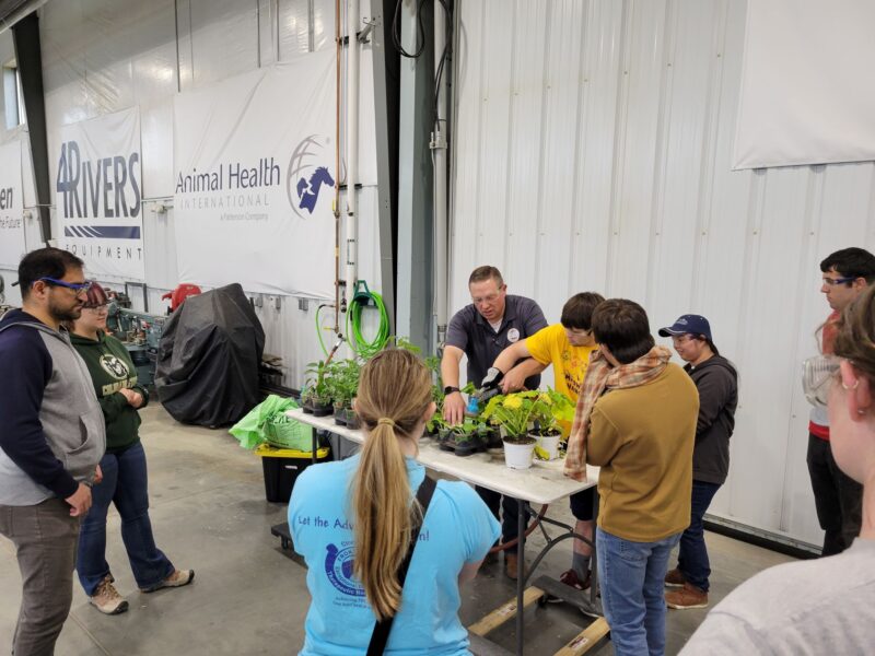 RAM Scholars work with plants inside big, open, white building.