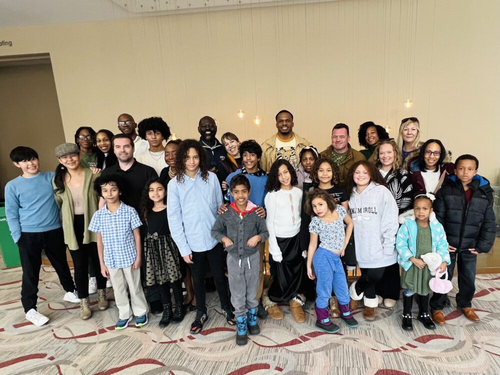 A group of Dandelions Rising participants and their families smile at the Fort Collins Lincoln Center.