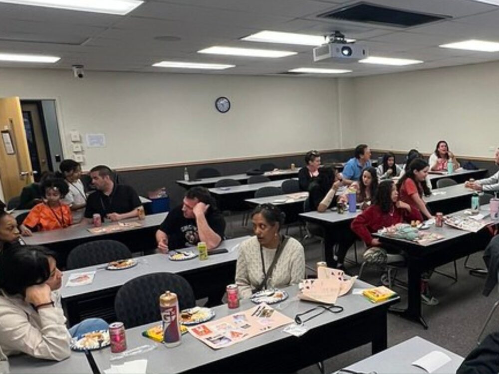 A group of Dandelions Rising participants engage in conversation in a classroom.