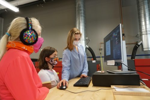 An instructor showing two students a lesson on the computer