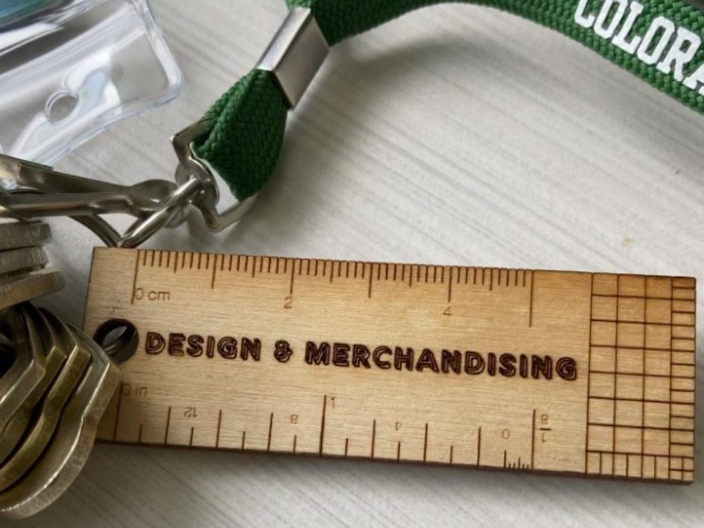 wooden keychain with `design & merchandising` laser cut onto it