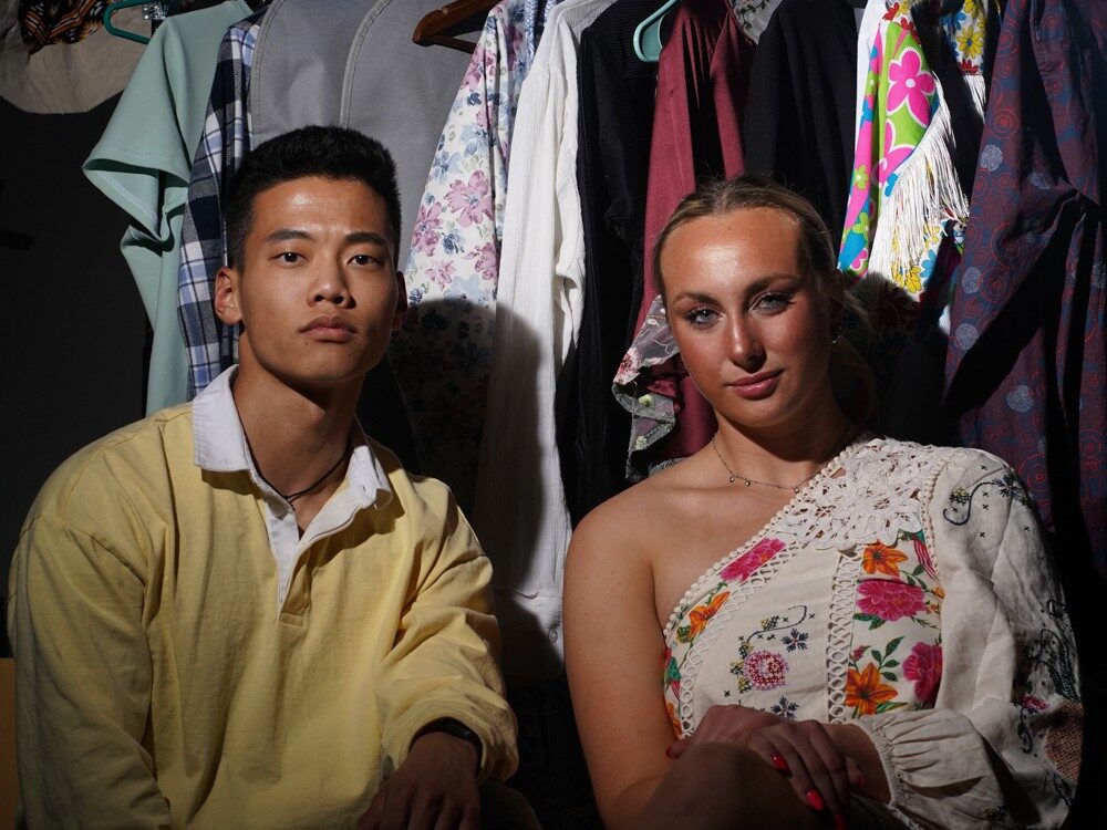 Fashion Show Directors Jason Thornton and Annie Lien pose in front of a garment rack
