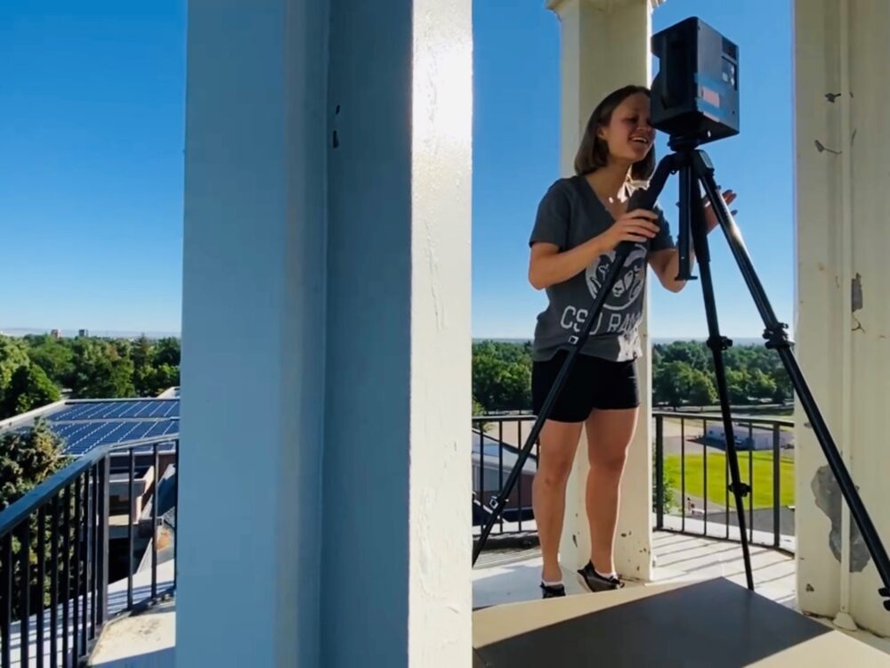 Reseach intern Amanda Spitzer levels uses the 3d Matterport camera on the roof of a building in Fort Collins.