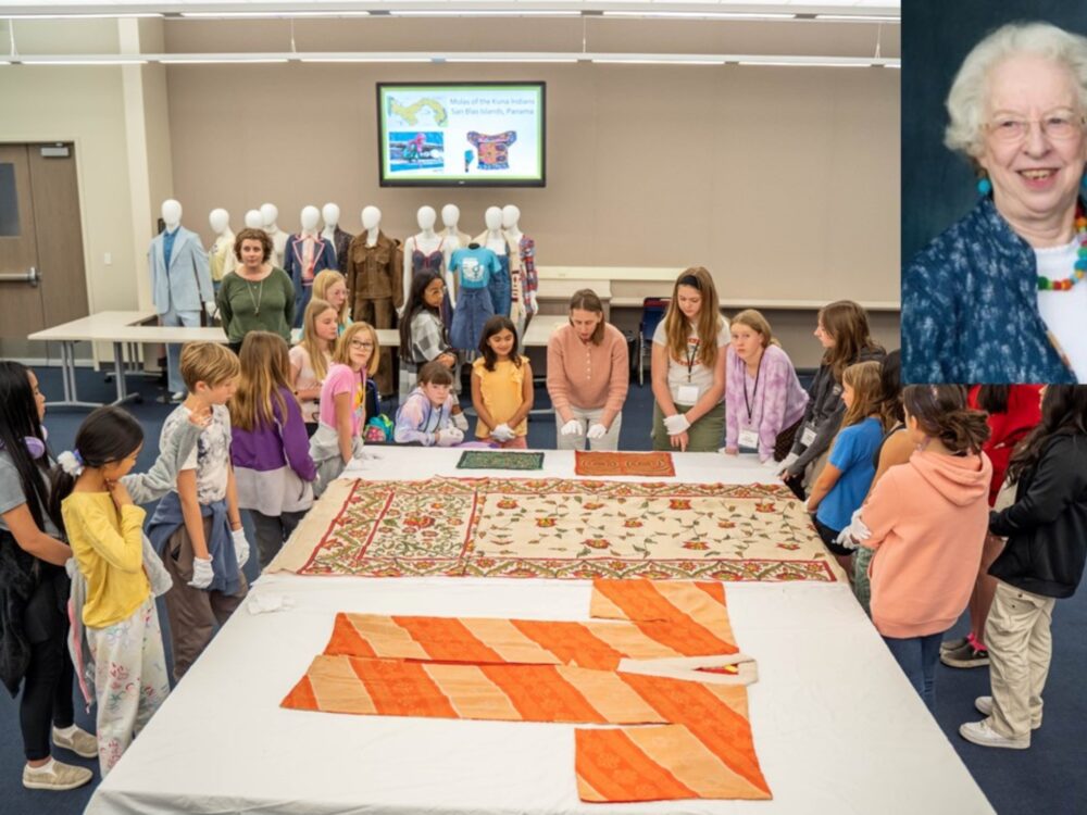 A large group of young students look at Kimonos laid on a table in the Avenir Classroom with an instructor, a headshot of Jan Else is overlaid in the top right corner.