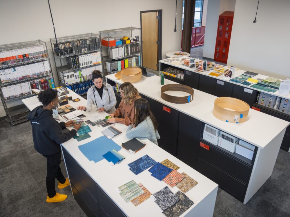 three students and a professor look at materials in the Design Library