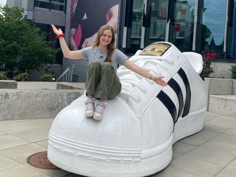 Opal, a student, sits on a giant Addidas shoe