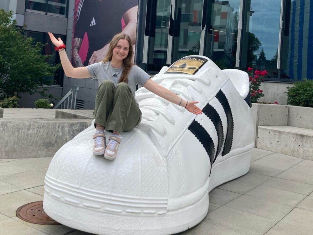 Opal, a student, sits on a giant Addidas shoe