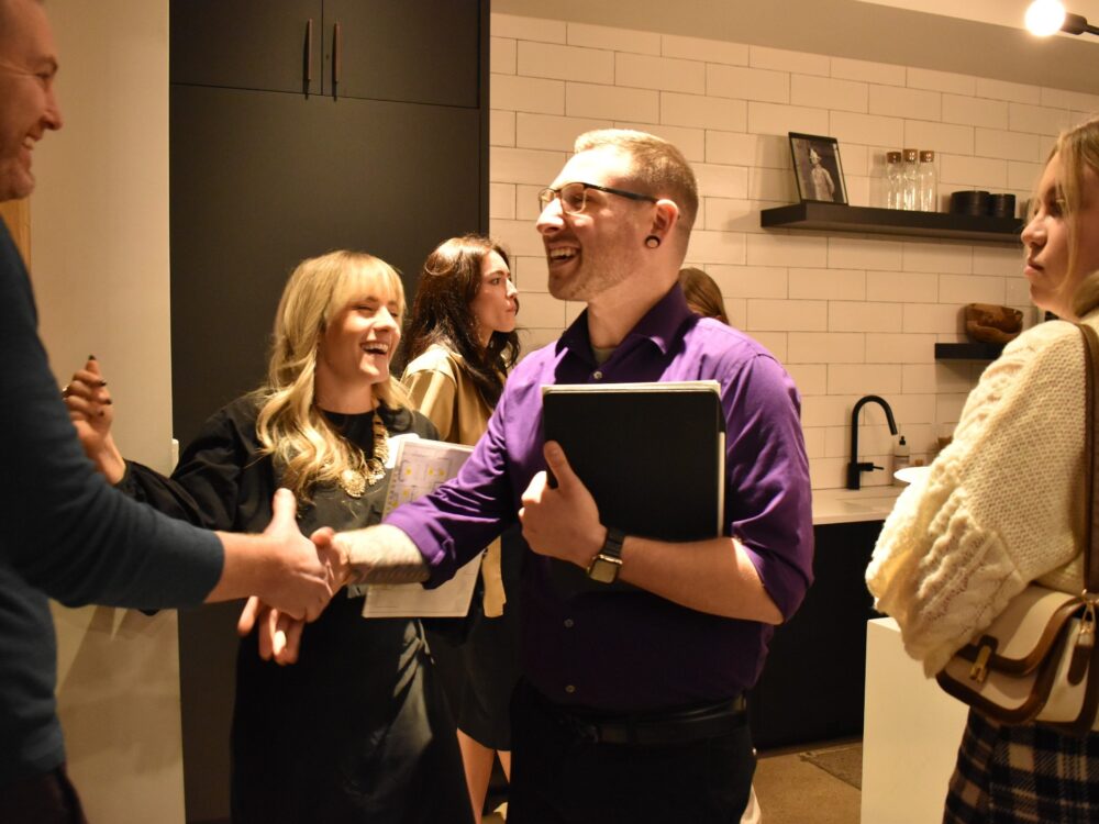 a student shakes hands with a design professional at a networking event