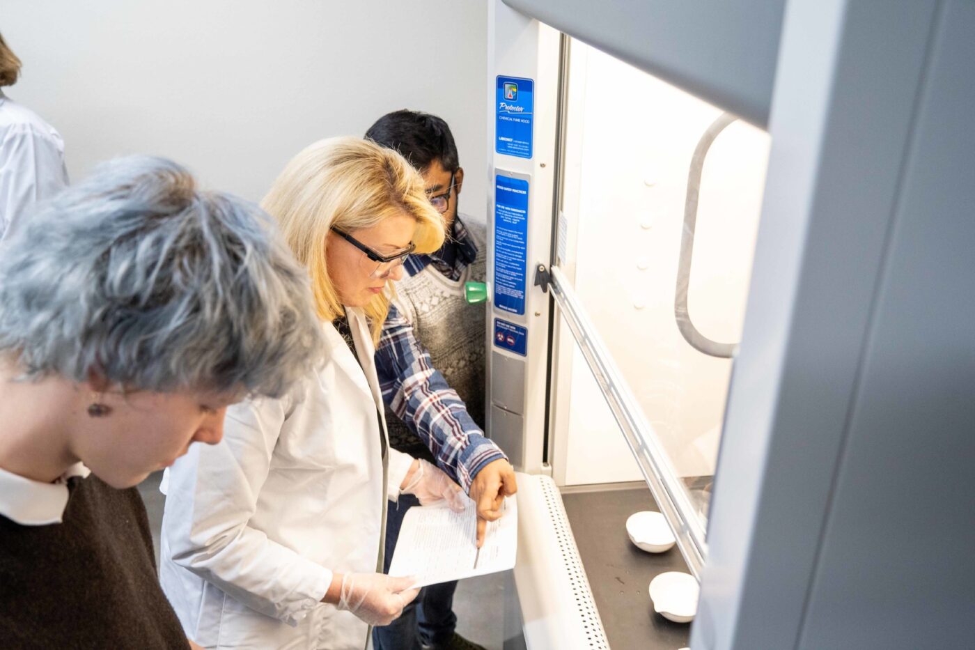 President Amy Parsons work with students to test fibers in the fume hood in the new textile science lab