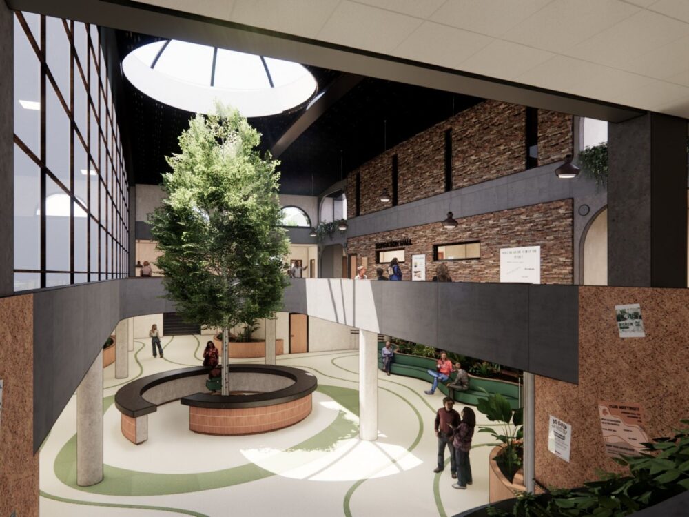 A multi‑level atrium featuring a central tree beneath a round skylight, curved walkways, cork wall panels, and people gathering in seating areas throughout the space.