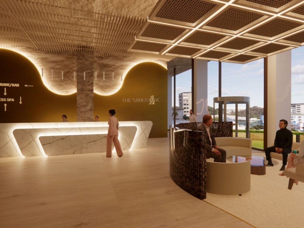 A sleek hotel lobby with a sculptural marble reception desk, gold accent wall labeled “THE SANDS,” modern seating pods, and floor‑to‑ceiling windows looking out to the city.