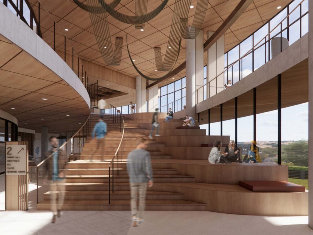 A large tiered wooden staircase doubles as a social seating area beneath sculptural ceiling elements, surrounded by expansive windows and upper‑level walkways.