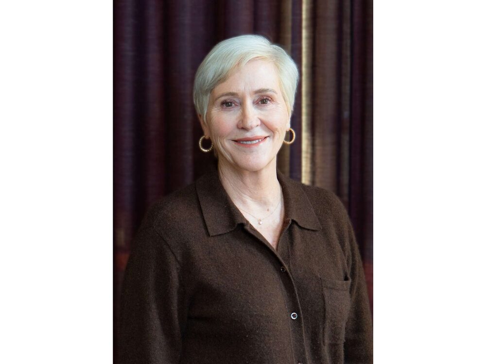 Portrait of Carla Dore in front of a wooden-paneled wall