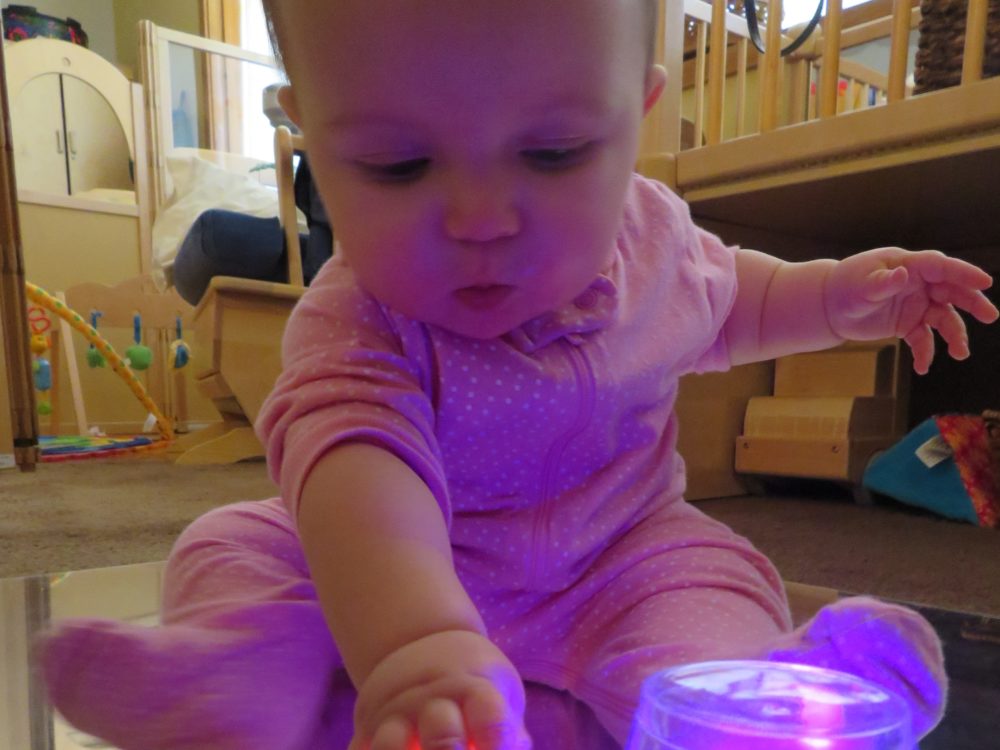 An infant plays with a light up toy