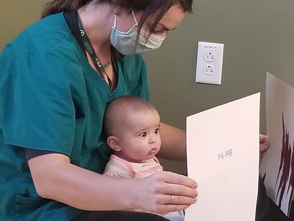 Caregiver holding a baby looking at paintings