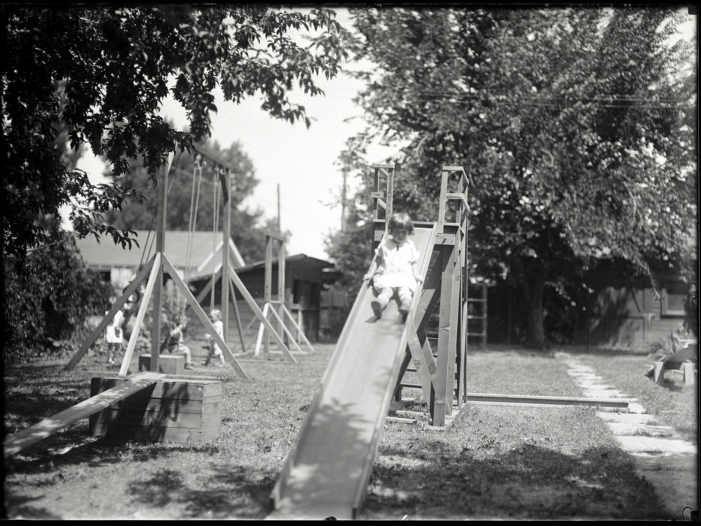 Black and white photo of a preschool child on a slide