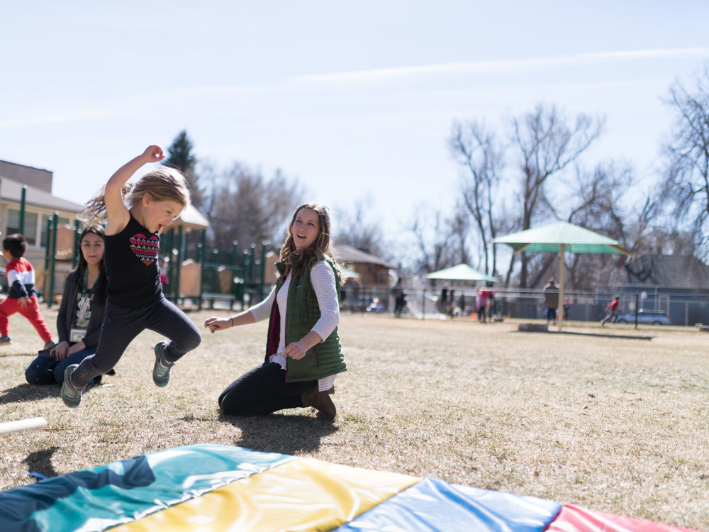 A child jumps on a playmat outdoors at the ECC