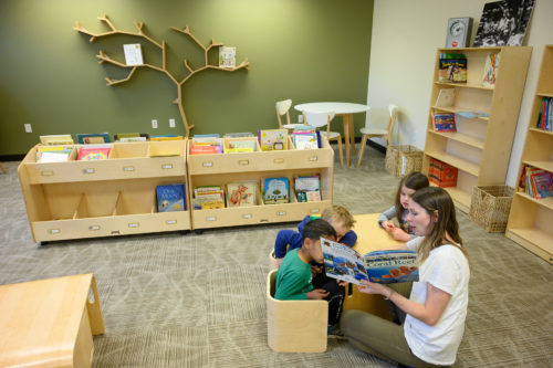A student reads with children in the new library space
