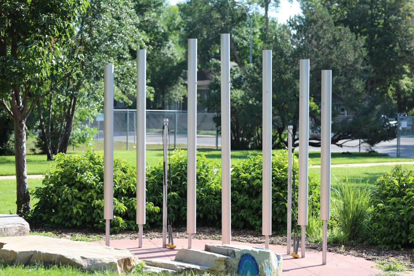 Tall chimes stand in outdoor musical garden with greenery around