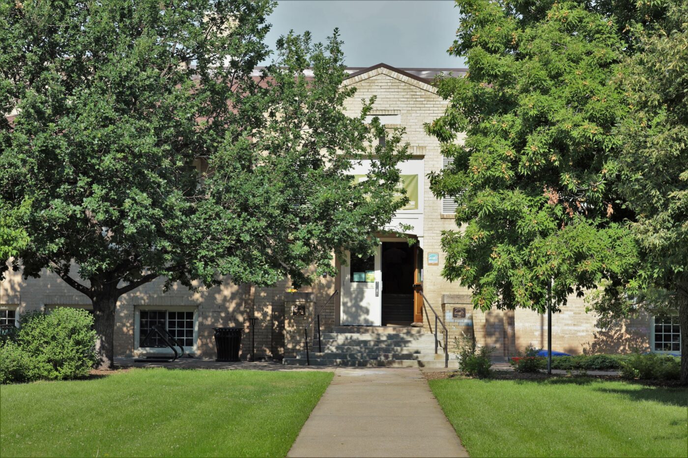 Brick building surrounded by big green trees.