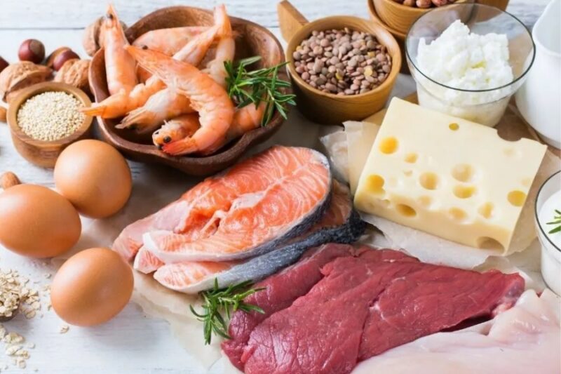 A collection of meats, cheeses, and eggs tastefully placed on a marble table.