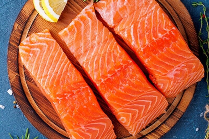 A zoomed in photo of salmon on a wooden plate
