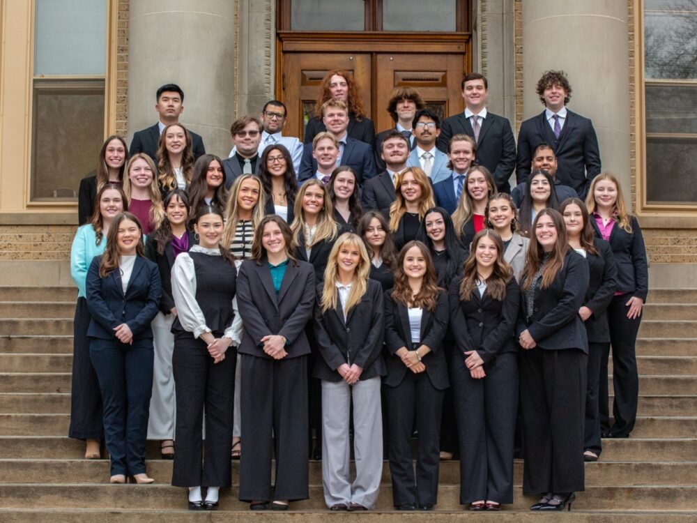 A group of CSU hospitality and event management students smile on the CSU administration building stairs.