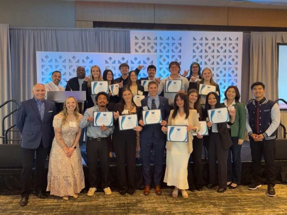 A large group of CSU hospitality and event management students smile while holding certificates