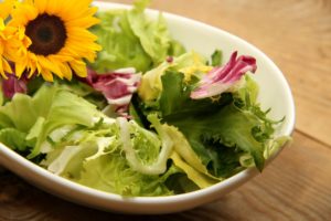 A salad in white bowl with a sunflower