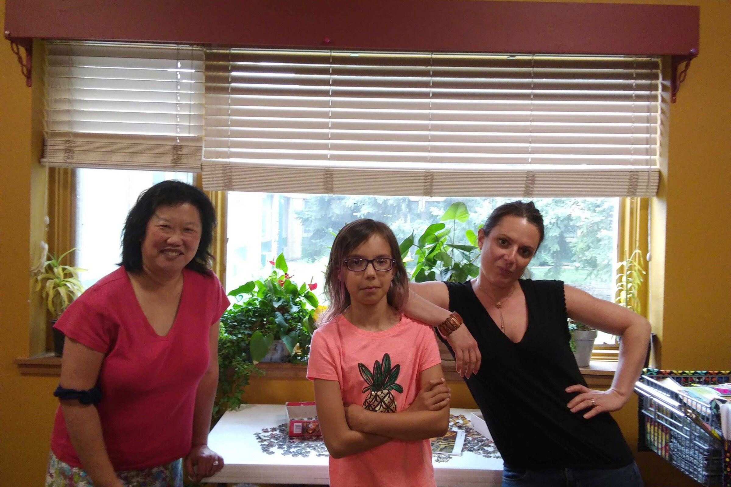 GRANDcares two adults and one child pose for a photo standing in front of a table with a puzzle