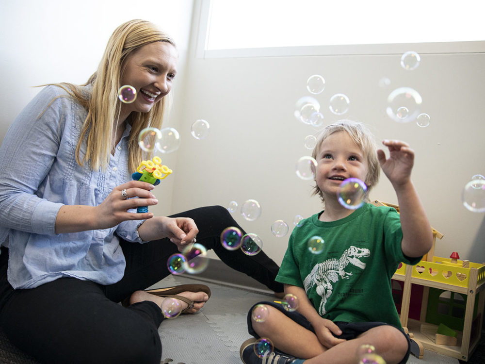 A graduate student blows bubbles with a research participant in the Developmental Disabilities Laboratory.